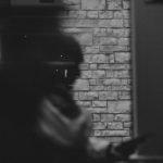 物陰からのぞく人物を写したモノクロ写真