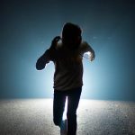 暗い道を走って逃げる人物のイメージ
