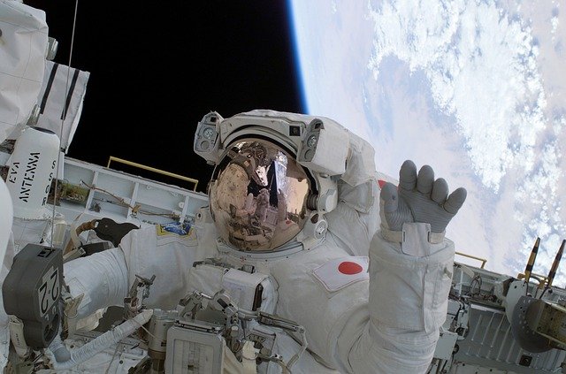 宇宙服を着た人物が、操縦しながら手を振っている