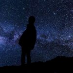 満天の星空の下で夜空を見上げる二人のシルエット