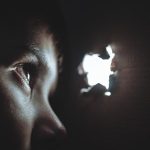 暗がりの中で穴を見つめる人物。不足や脆さに気づく心の状態を象徴している