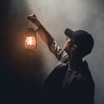 ランタンを掲げる人の姿。暗闇の中で導きを示す案内人の夢のイメージ