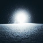 暗闇の雪原に差し込む強い光が試練と再生を象徴するイメージ