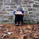 夢の中で壁の前に座り込み、行き詰まりや限界を感じている人物の後ろ姿 
