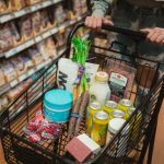 スーパーの売り場で商品が入ったショッピングカートを押している手元のイメージ