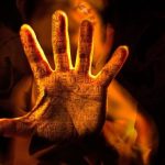 「憑依や乗っ取られる夢の不安を象徴する、炎に浮かび上がる模様入りの手｜mystic hand with glowing symbols representing spiritual influence in dreams」
