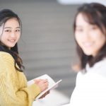 ノートを手にこちらを見返す女性と、ぼんやり映るもう一人の女性。人の姿や雰囲気が誰かを連想させるイメージ。