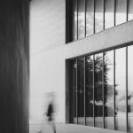 建物の通路を歩く、ぼやけた人影のモノクロ写真