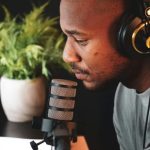 ヘッドホンをつけてマイクの前で集中する人物