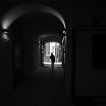暗いアーチ型通路を歩く人物のシルエット