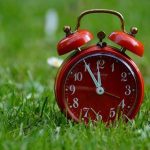 チャイムやベルの音で目覚める夢のイメージ（赤い目覚まし時計）