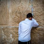 石の壁に両手をつき、うなだれる男性。
行き詰まりや限界、努力しても突破できない状況を象徴する夢のイメージ。
A man leaning against a stone wall with his head down, symbolizing obstacles, frustration, and inner limitations in dreams.