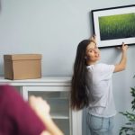 部屋に絵を掛け替えている女性