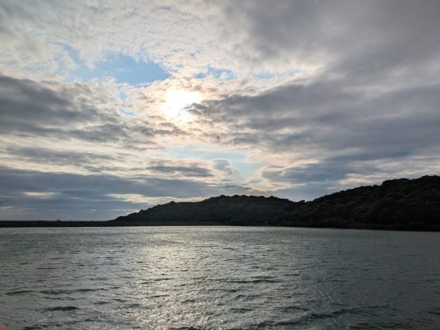 雲の切れ間から光が差す水辺の風景