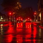 雨で濡れた夜の道路に赤いブレーキランプが反射している様子