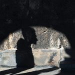 壁に映った人物の横顔の影。光と影が交差し、不安や思い込みを象徴している。