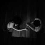 暗い部屋でテーブルを挟んで向き合う二人