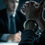 夢の中の犯罪を象徴する手錠と取り調べのイメージ｜Handcuffed suspect under interrogation symbolizing crime dreams