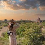 明るい空の下、広大な景色を見つめる女性。意識の覚醒や明晰夢の自由な心を象徴するイメージ。Woman gazing at the horizon under a bright sky, symbolizing awareness and freedom in lucid dreams.