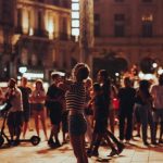 夜の広場で人々の中に立つ女性