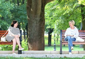 公園のベンチで距離を置いて向き合う二人の女性。不倫相手の妻や夫が出てくる夢が示す、心の葛藤や現実感覚を象徴するイメージ。