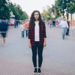 人通りの多い街で、一人だけ立ち止まり周囲との違和感を感じている女性