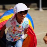 トンネルをくぐり抜け、全力で走る子ども。 挑戦・努力・成長を象徴する夢のイメージ。 A child running out of a colorful tunnel during a sports day event, symbolizing effort, growth, and healthy competition in dreams.