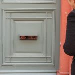扉の郵便口から覗く子どもの目。回覧板を通じた人間関係や、心の交流を象徴する夢のイメージ。