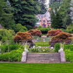 立派な庭園の奥にそびえるマナー（邸宅）。富・ステータス・心理的な距離や威圧感を象徴する風景。