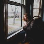 窓辺で静かに休む女性。心が疲れて回復を必要としている様子 