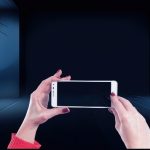 「暗い空間でスマートフォンを構えて動画を撮影する手元のイメージ。記録された映像やYouTube動画を象徴する写真｜recording video symbolic image」