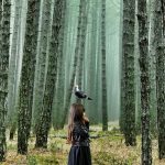 森の中に立つ女の子と鳥の姿が、子どもが大人たちの選択や未練を静かに見ている心情を表している