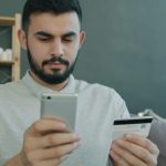 仕事の内容を確認して報酬が0円だと気づく夢を象徴する、スマホとカードを見つめる男性