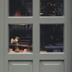 ドア越しに見える室内の灯りと花（クリスマスの夢・善意が巡るイメージ）