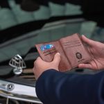 屋外で財布を開き、中身を確認している様子。現実的な不安や責任感を感じさせる場面