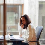 周囲に人がいる中で、任された仕事について考えながら作業する女性の様子