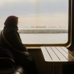 窓辺に座り外の景色を静かに見つめるおばあさん