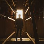 光の差す通路の奥に立つ不審な人物