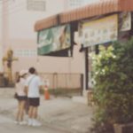 少しぼやけた街角で、寄り添うように立つ二人の後ろ姿
