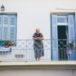 ベランダに立ち、静かにこちらを見つめる年配の女性