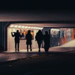 青白い光を背に歩く複数の人影のシルエット