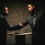 暗い場所で向かい合い握手する二人の男性