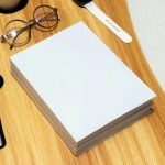 作業机に置かれたコピー用紙とメガネ。必要なものを整理する夢のイメージ