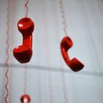 赤い受話器が複数ぶら下がっている、電話が混線する夢のイメージ