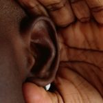 耳に手を当てる人物が、盗聴される夢に表れる会話を聞かれる不安を表している