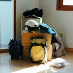 部屋の隅に段ボールやバッグが積まれ、荷物が増えてまとまらない様子